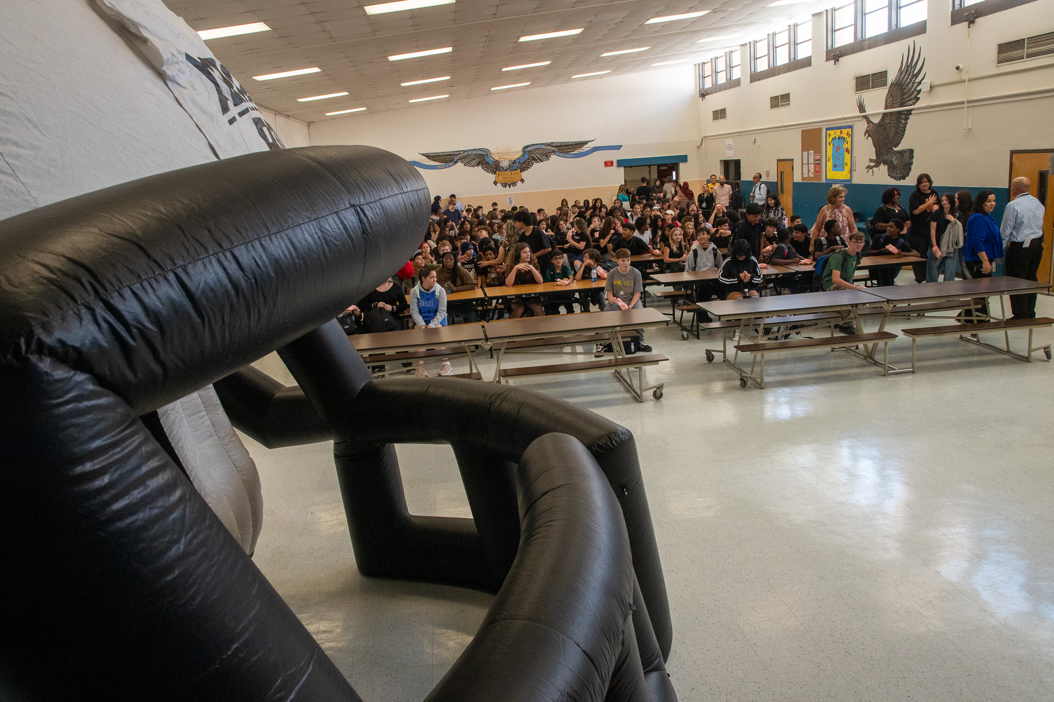 An inflatable football helmet sits at the front of the cafeteria while students sit waiting for an announcement