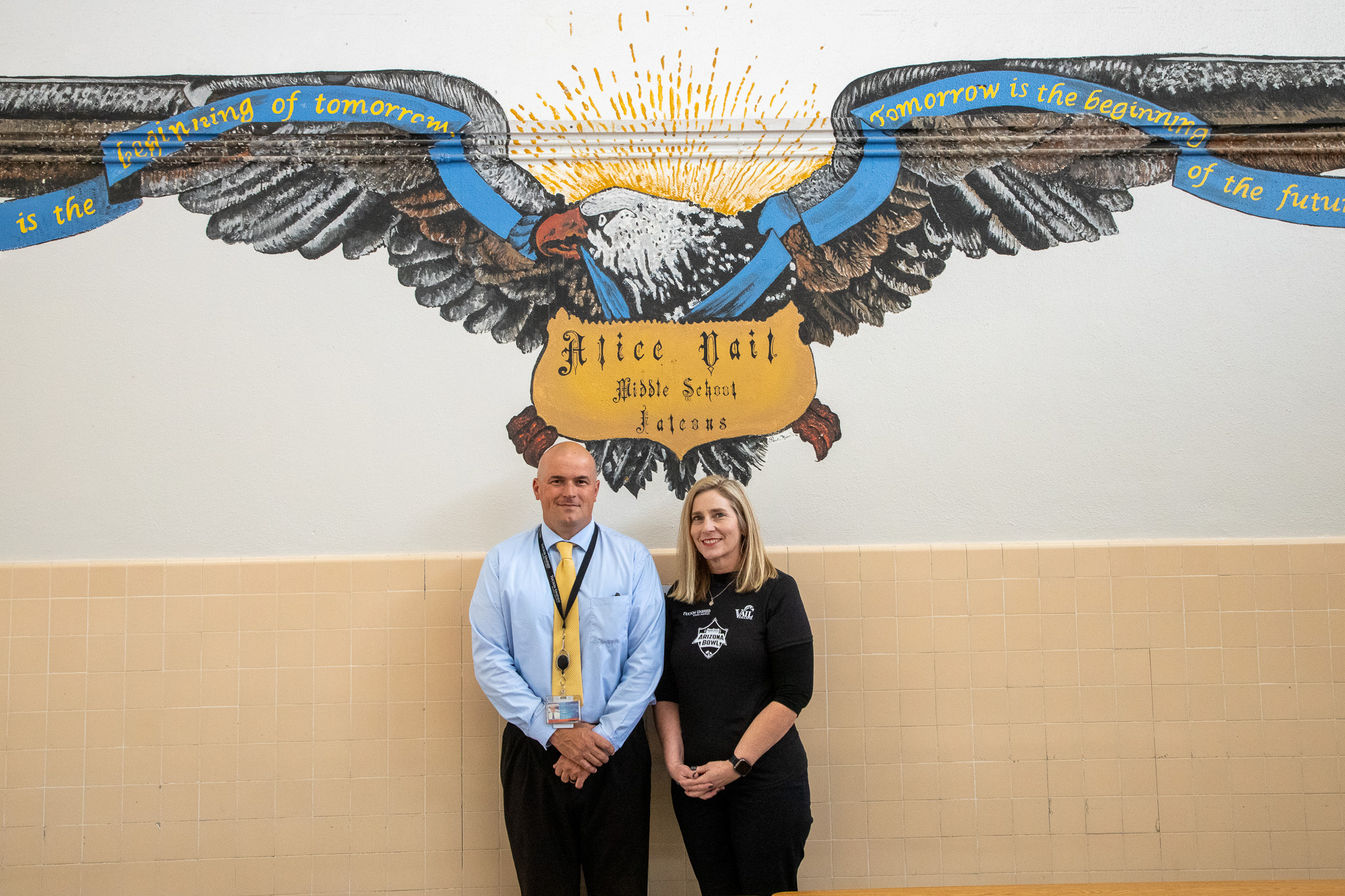 Vail's principal and AP smile in front of a falcon mural